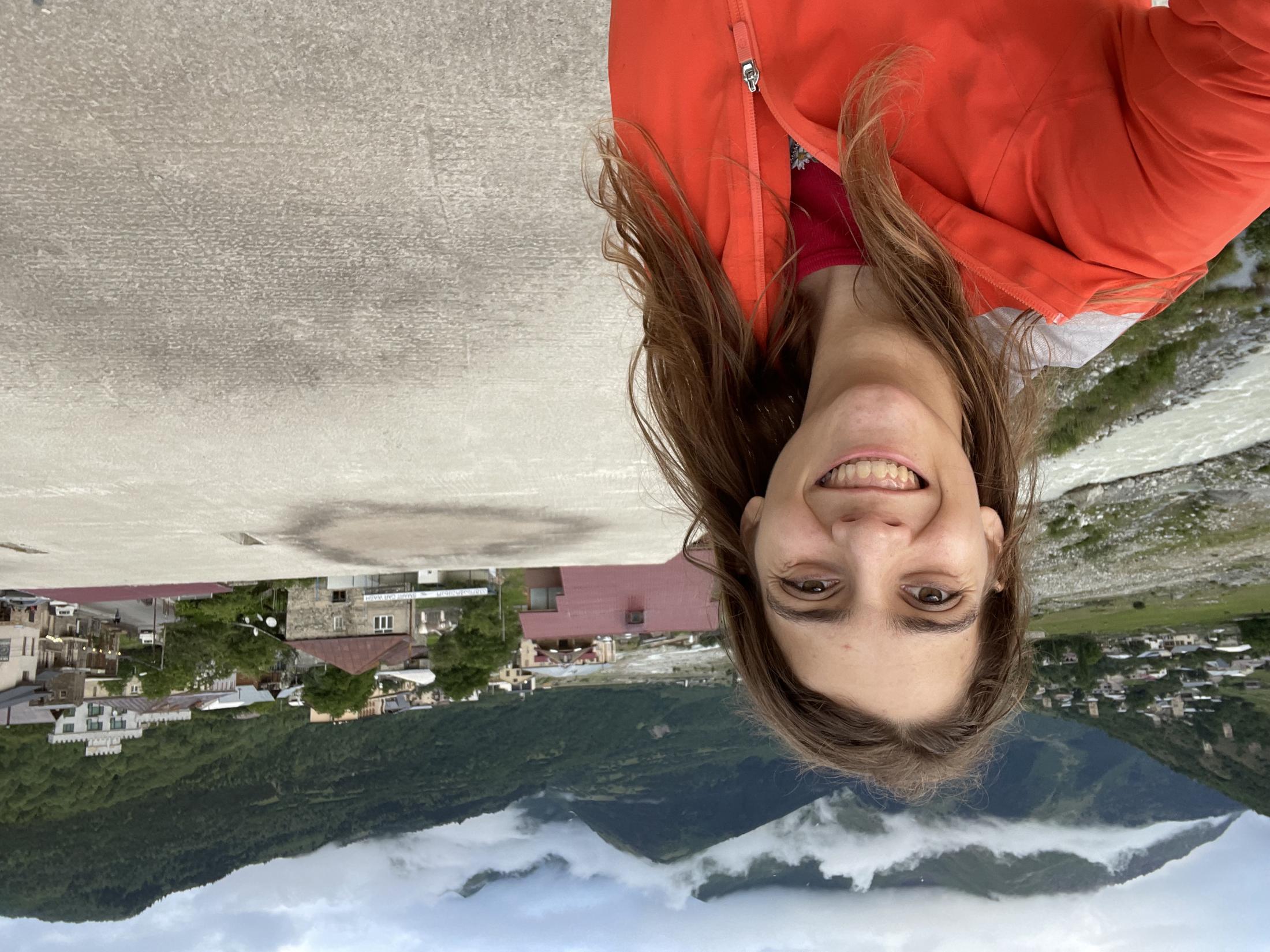 Darian Lee stands in a red jacket in front of a scenic view.
