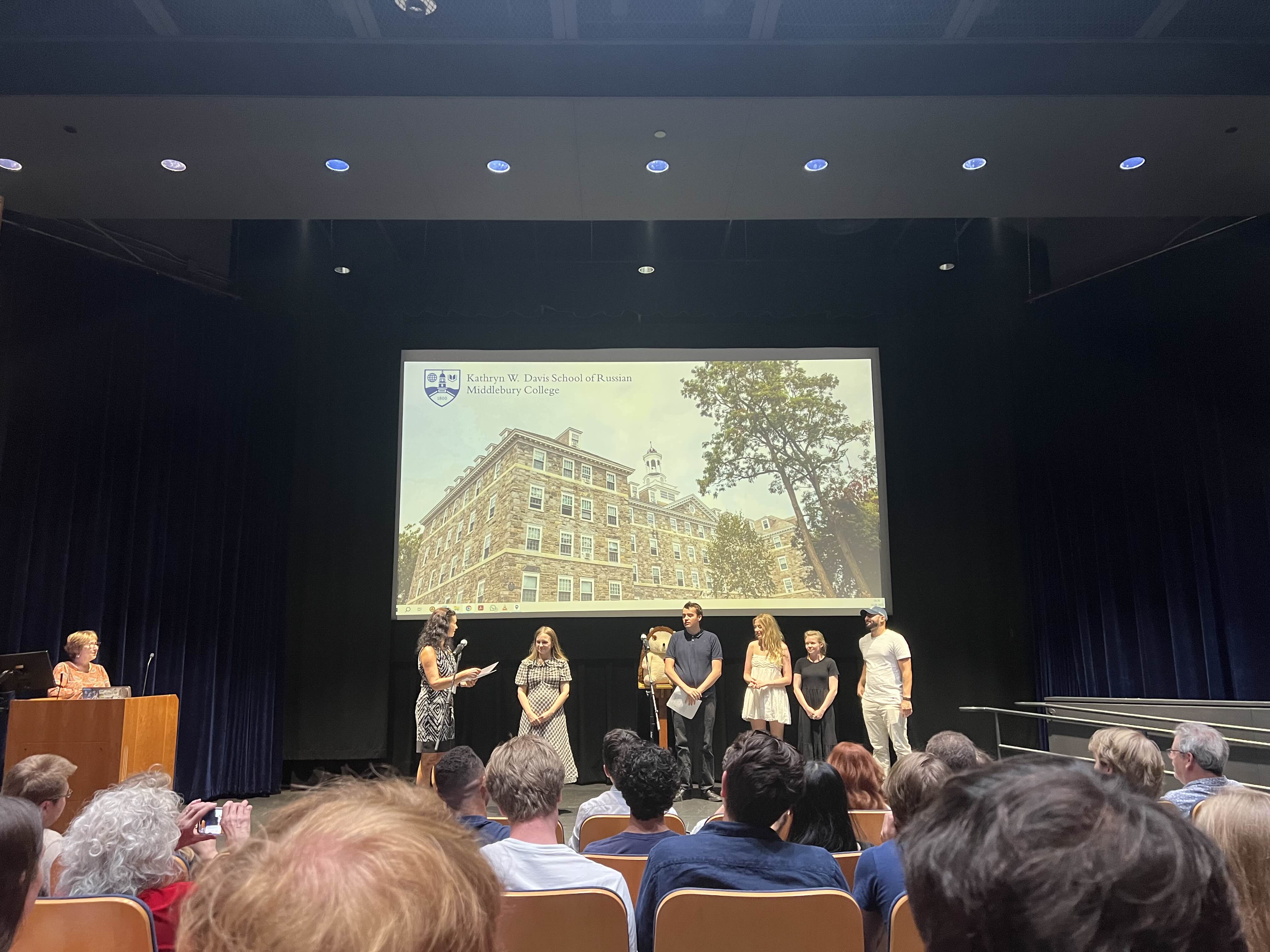 A group of people stand on a stage during a presentation.
