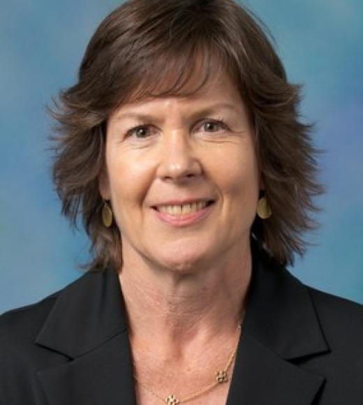 Josephine Andrews smiles at the camera in front of a blue background.