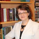 Liliana Avramenko stands in front of a bookshelf, smiling at the camera.