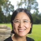 Woman in glasses in front of a grassy field