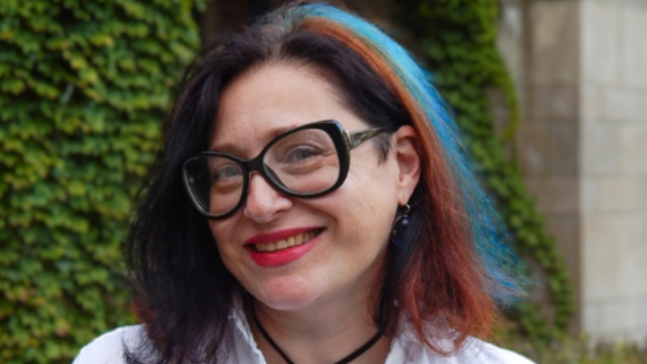 A portrait of a woman with a blue and red streak in dark hair.