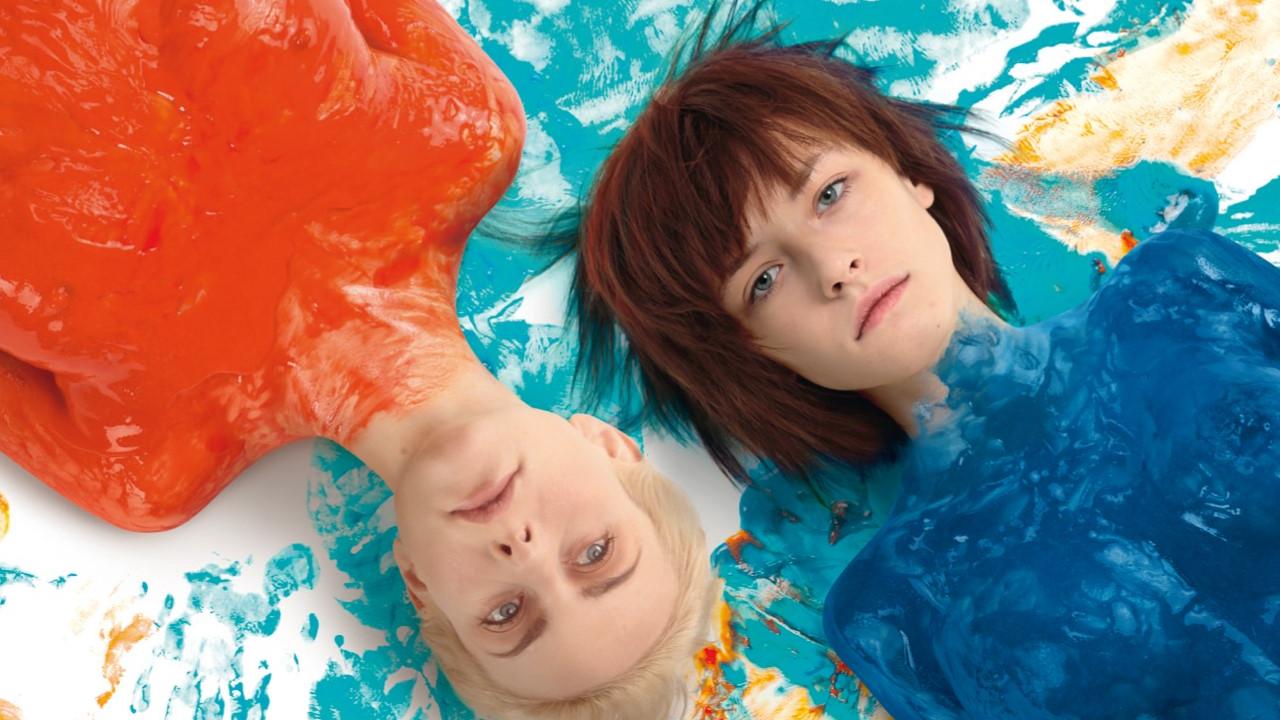 Two women, bodies covered in orange and blue paint