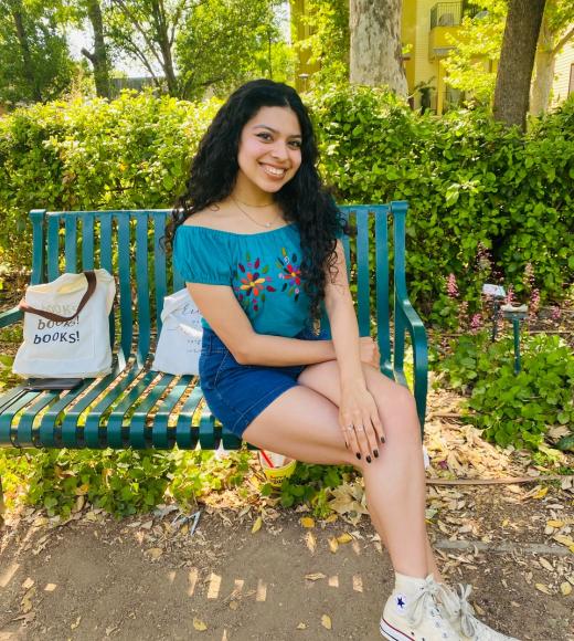 A woman on a bench near a bag that says "Books! Books! Books!"