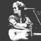 a black and white photo of a rock and roll musician and their guitar