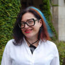 A portrait of a woman with a blue and red streak in dark hair.