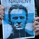 A person's hands holding a blue tinted posted of a man with the word "Navalny" above